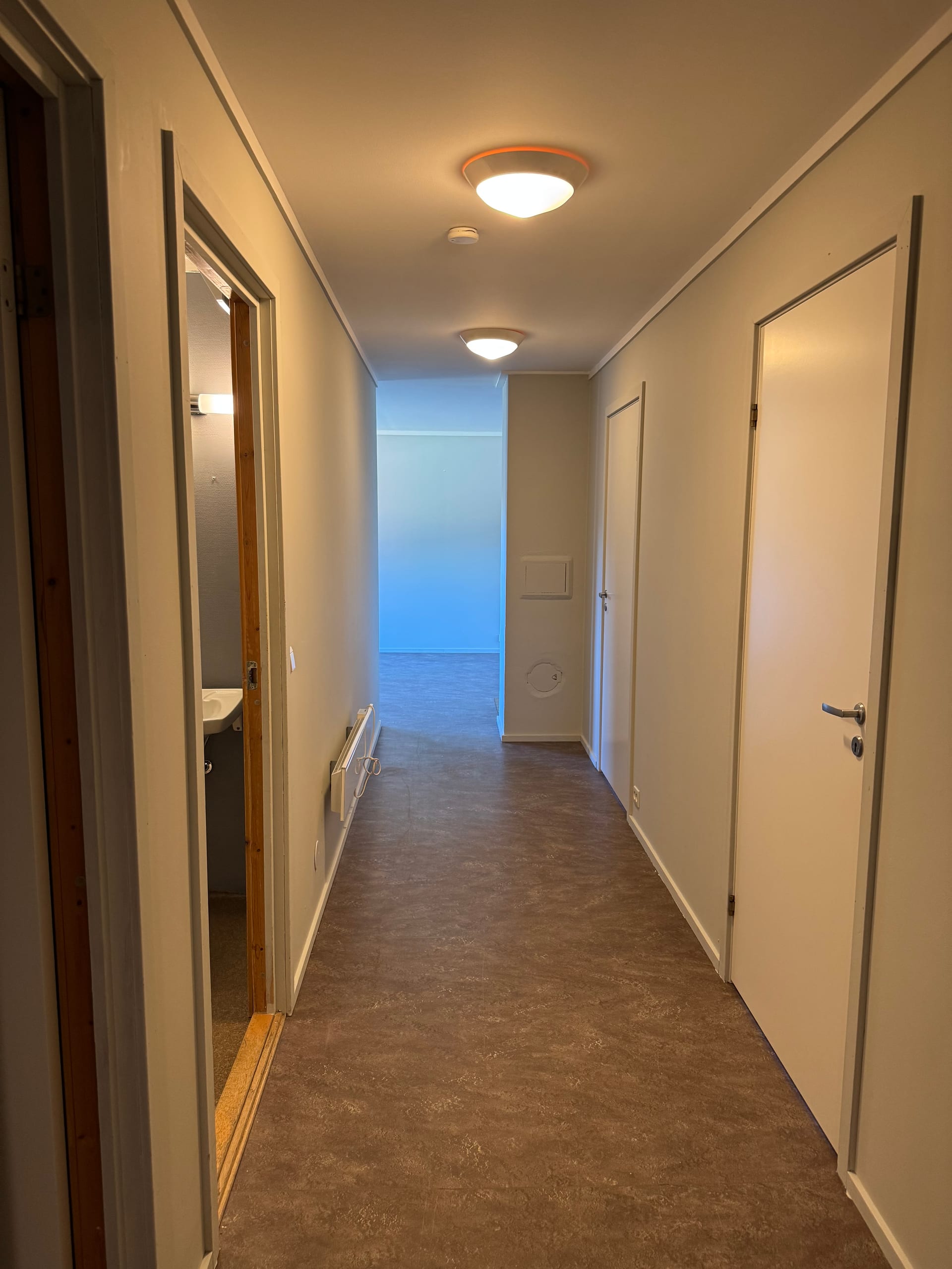 Gang med flere dører og mørkt gulv
